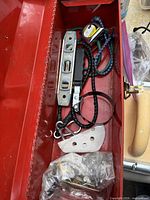 Open red metal toolbox with various tools inside