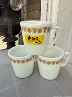 Three Pyrex Butterfly Gold milk glass mugs stacked