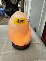 Lamp illuminated showing salt crystal formation, base, cord, and price sticker