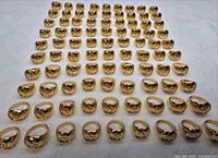 Full set of 100 gold-coloured Om signet rings arranged in rows