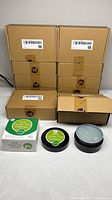 Stack of ten sealed brown retail boxes plus one display jar and sleeve box