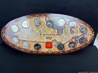 Front view of entire 1999 Millennium quarter set on oval map board showing 12 coins and medallion