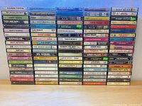 Full front view of about 95 cassette tapes arranged in rows showing spine titles