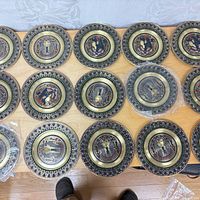 All 15 brass enamel plates on table