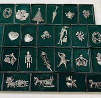 Overall view of 23 boxed pewter pins showing variety of motifs