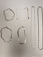 All six sterling silver pieces laid out: three bracelets top row, three necklaces bottom row