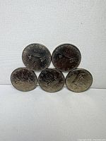 Front view of five 1975 Canadian Voyageur dollars showing reverse canoe design