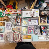 Overall view of assorted boxed and loose household, craft and game items on table