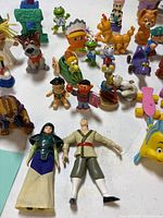 Overview of assorted Disney, Sesame Street and other figurines on table