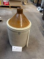 Full view of crock showing gray body, brown glazed top, blue 5 stamp and scale for height