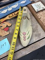Cream painted wooden shoe hanging, blue peg rack, dog plaque visible with tape measure for scale