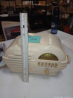 Front and top view of cream bakelite Belmont radio with ruler for scale, showing dial, push buttons and knob