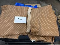 Folded brown and white geometric patterned lined curtain panels with tie