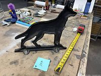 Front/side view of cast iron dog doorstop with measuring tape showing length