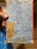 Underside of jewelry box with blue patterned paper and partial label