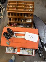 overview of tackle box open with contents, reels, rod visible