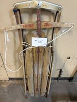 Front view of full sled showing wood slats, steel runners, logo and rope