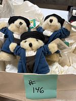 Three identical Columbear plush bears in box showing clothing and tags