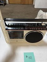 Front view showing cassette deck, speaker, controls and ruler for scale