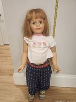 Front view of Patti Playpal doll standing against wall showing full outfit and size reference tape