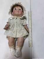 Full view of doll next to ruler displaying size and outfit