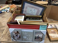 Box containing assorted frames and prints, front view shows collage frame and variety of other frames