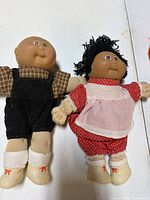 Two Cabbage Patch Kids dolls in outfits, corduroy overalls and red polka dot romper