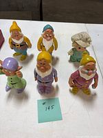 Front view of five Disney dwarf figurines and one Precious Moments doll