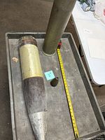Overall view of projectile, casing and nose cone with tape measure for scale