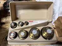 Open case displaying all seven brass weights and internal model label