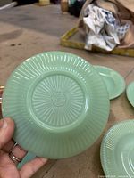 Front of saucer showing radial fluted rim pattern and pale green color