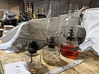 All three oil lamps side by side showing sizes, chimneys, wall bracket