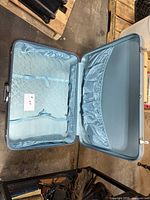 Open large light blue suitcase showing interior lining and pockets