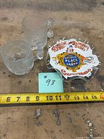 Overview of two mugs and ashtray with ruler for scale