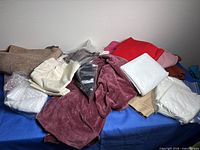 Overview of mixed fabric pieces on table including burgundy velvet, white, tan, black, red and more