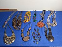 All ten assorted necklaces laid out on blue cloth