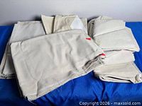 Stack of several folded cream fabric pieces on blue surface