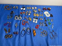 Full overview of all earrings laid on blue cloth