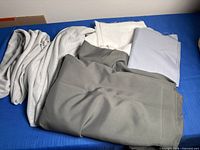 Group of five folded grey fabrics showing different shades and patterns