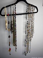 Multiple necklaces of various styles hanging on black hanger