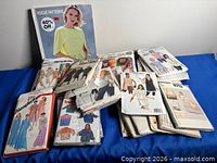 Overview of Vogue Patterns book and stack of pattern envelopes on blue surface
