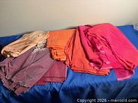 Group of five folded fabric pieces in various pink, coral and orange shades on blue surface