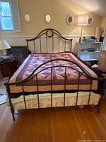 Front view of assembled metal queen bed frame with mattress and quilt
