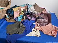 Overview of basket and bin filled with varied fabric pieces on blue table