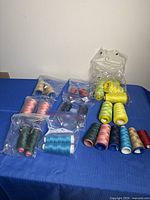 All thread cones grouped on table, bagged and loose, showing colour range