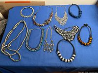 Group shot showing all necklaces and earrings on blue surface