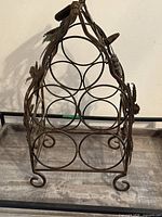 Front view showing six circular bottle holders, grape leaf decorations, scrolled feet