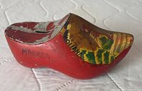 Side view of red wooden clog showing Marken inscription and paint loss