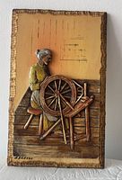 Front view of carved panel showing figure, spinning wheel, signature