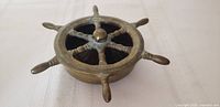 Top angled view of six-spoke brass ship wheel ashtray showing overall form and patina